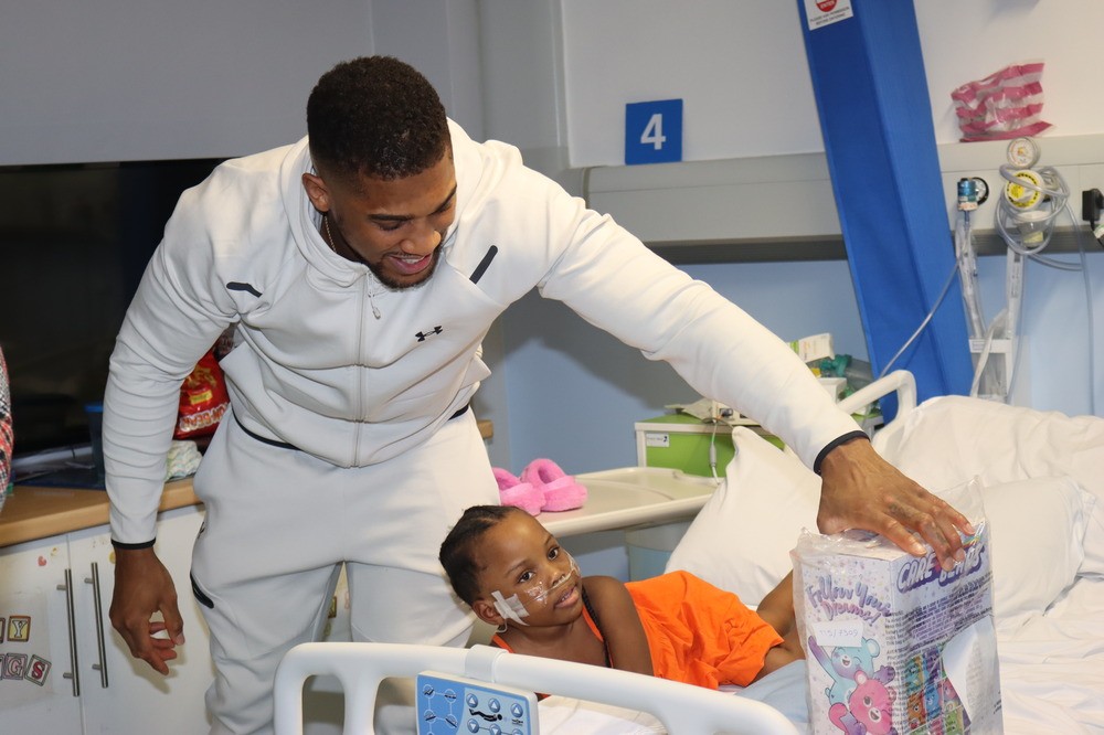 Anthony Joshua giving a gift to child in hospital bed