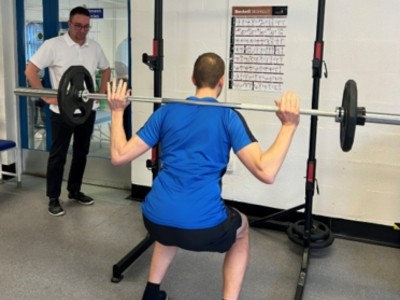 A physiotherapy patient lifts weights while a physiotherapist watches